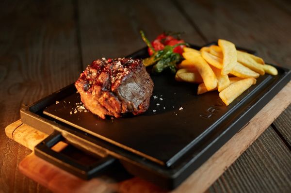 Corte de carne servido sobre piedra caliente con papas fritas en Dreams Playa Esmeralda Resort & Spa