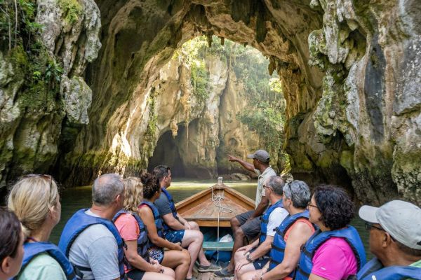 Turistas explorando cueva de piedra caliza en Los Haitises