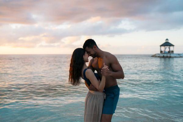 Pareja bailando entre las olas del mar en la playa de Secrets Playa Esmeralda Resort & Spa