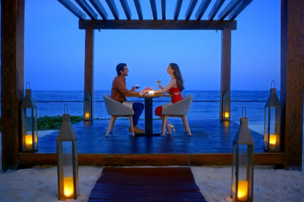 Mesa decorada para una cena romántica en la playa de Secrets Playa Esmeralda Resort & Spa