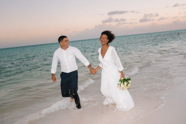 Novios jugando entre las olas del mar en Secrets Playa Esmeralda Resort & Spa