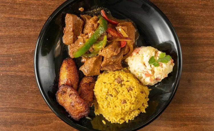 Plato típico dominicano con arroz, carne guisada, plátano maduro y ensalada, reflejo de la gastronomía local de Miches.